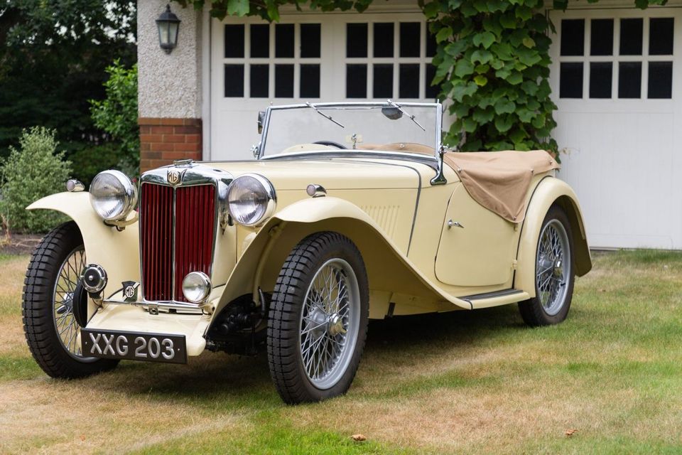 A cream MG TC photographed in front of a garage